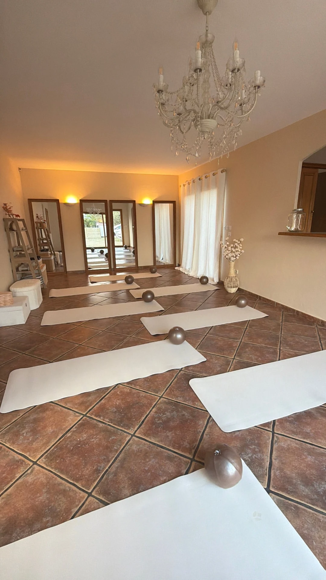 Salle du studio Elea Pilates, miroirs et lustre au-dessus des tapis
